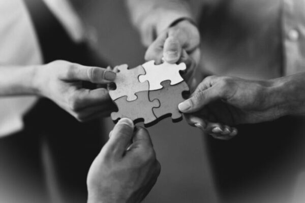 dłonie czterech osób składają w całość cztery puzzle
